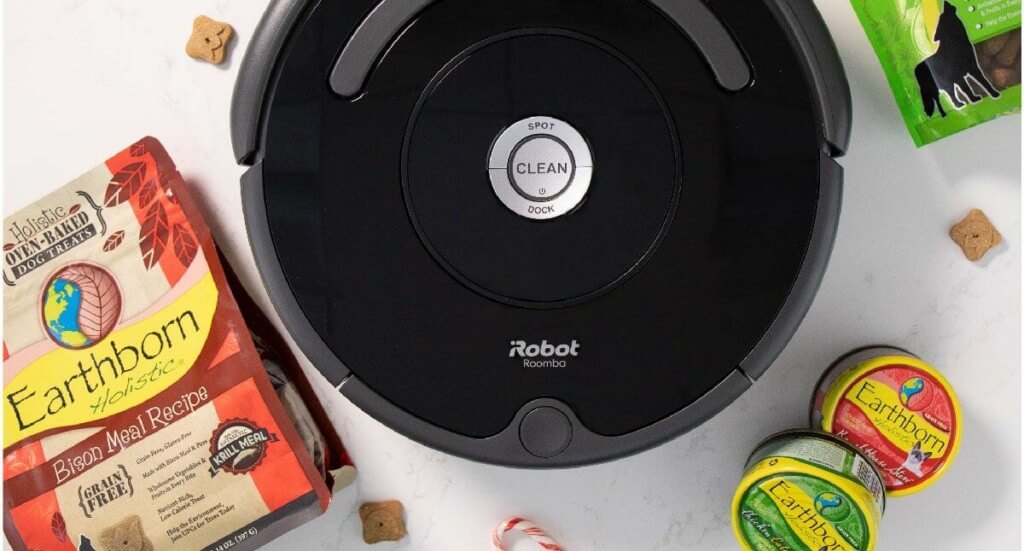 An overhead shot of an iRobot Roomba 675 with Earthborn Holistic dog treats and cat food scattered around