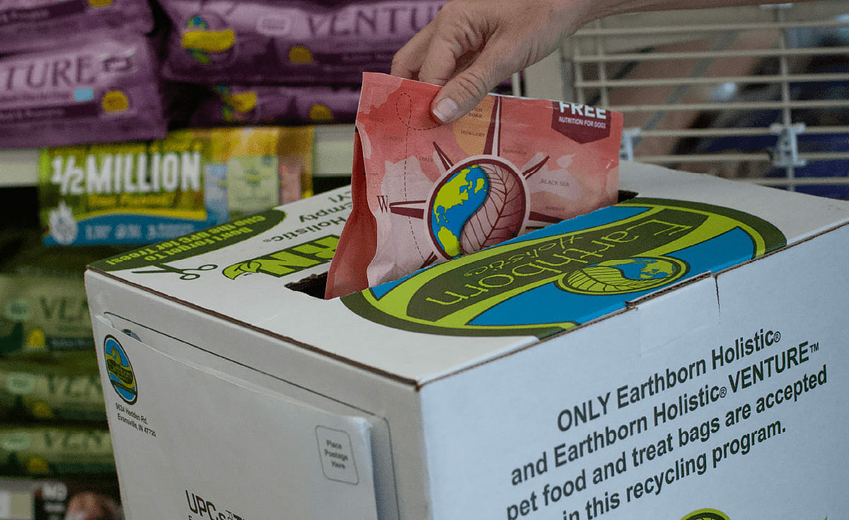 A person dropping a food bag into an Earthborn ReBorn recycling bin