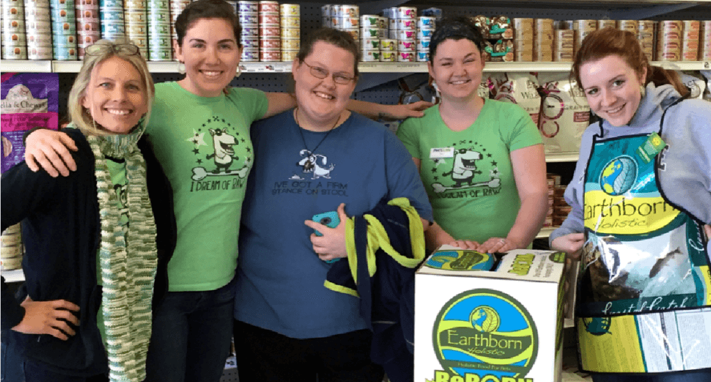 Pet store employees stand next to a Earthborn ReBorn recycling bin