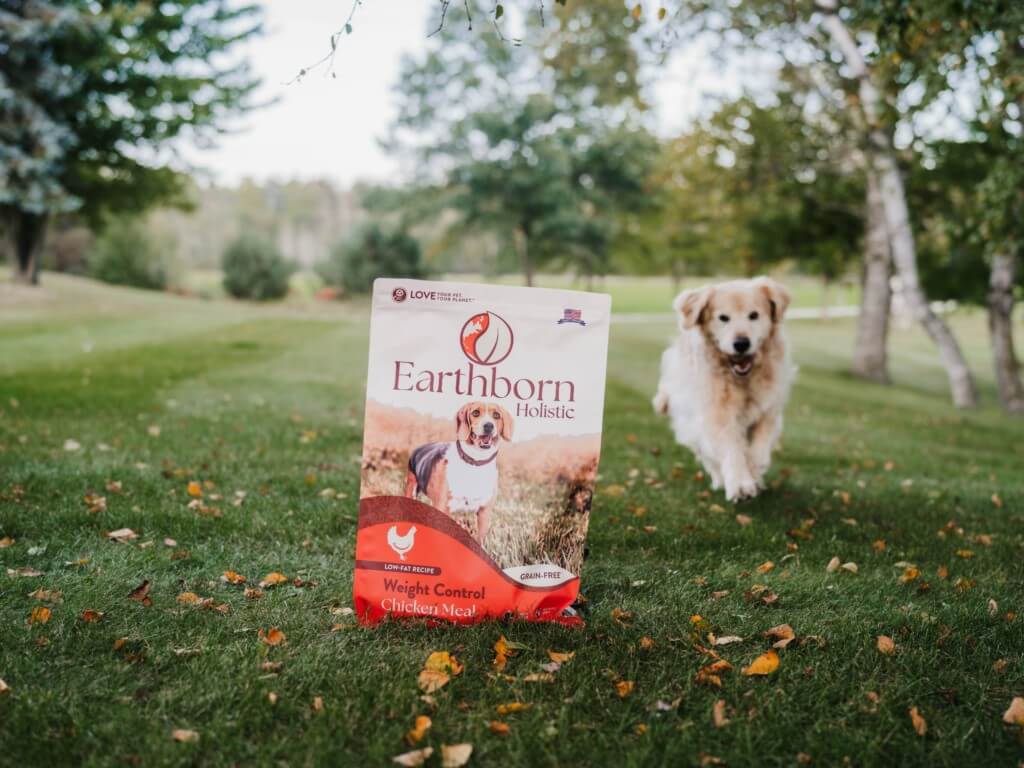 Dog running towards a bag of Earthborn Holistic Weight Control