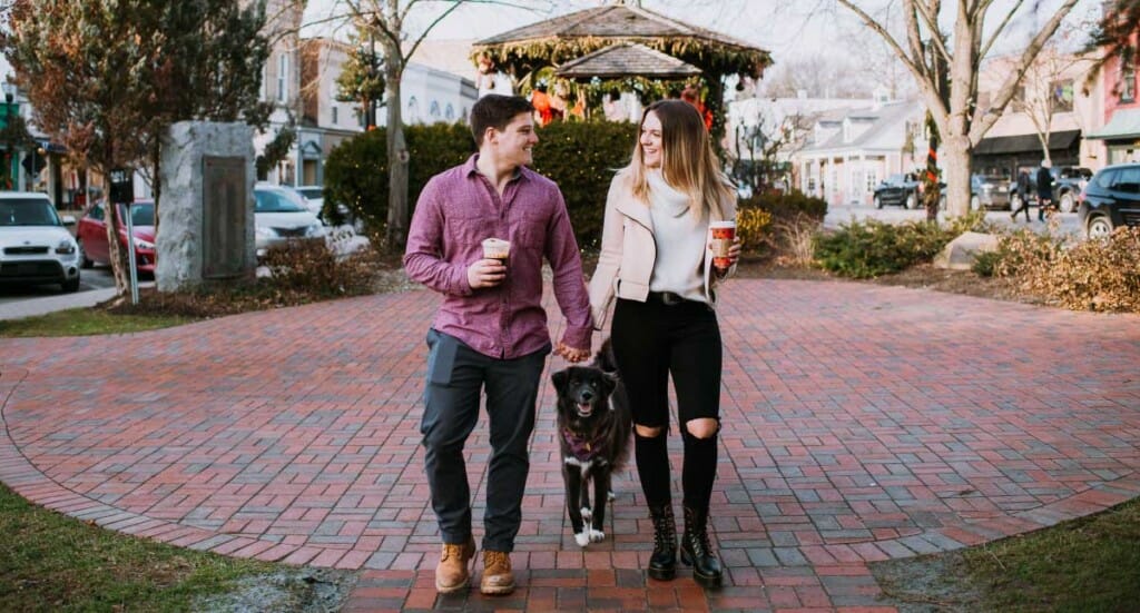 A couple walks through downtown Cleveland with their dog trailing behind