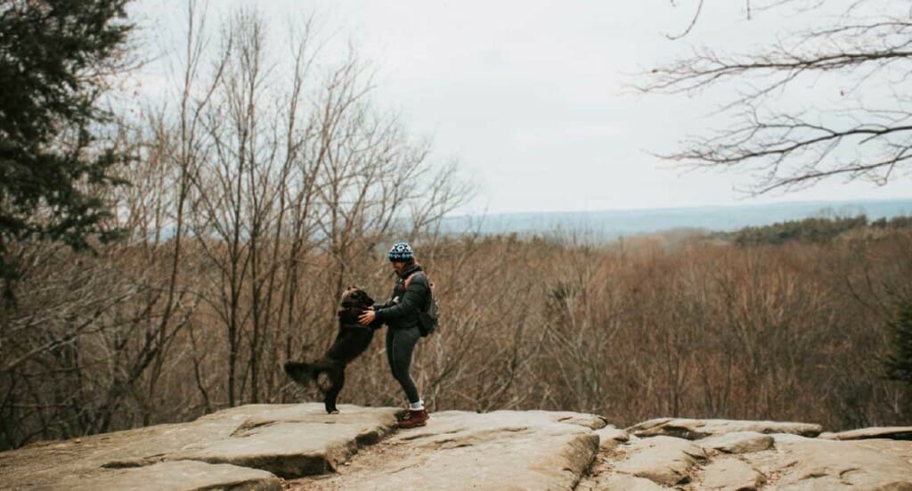 A woman and her dog stand on an overlook on a Cleveland hiking trail