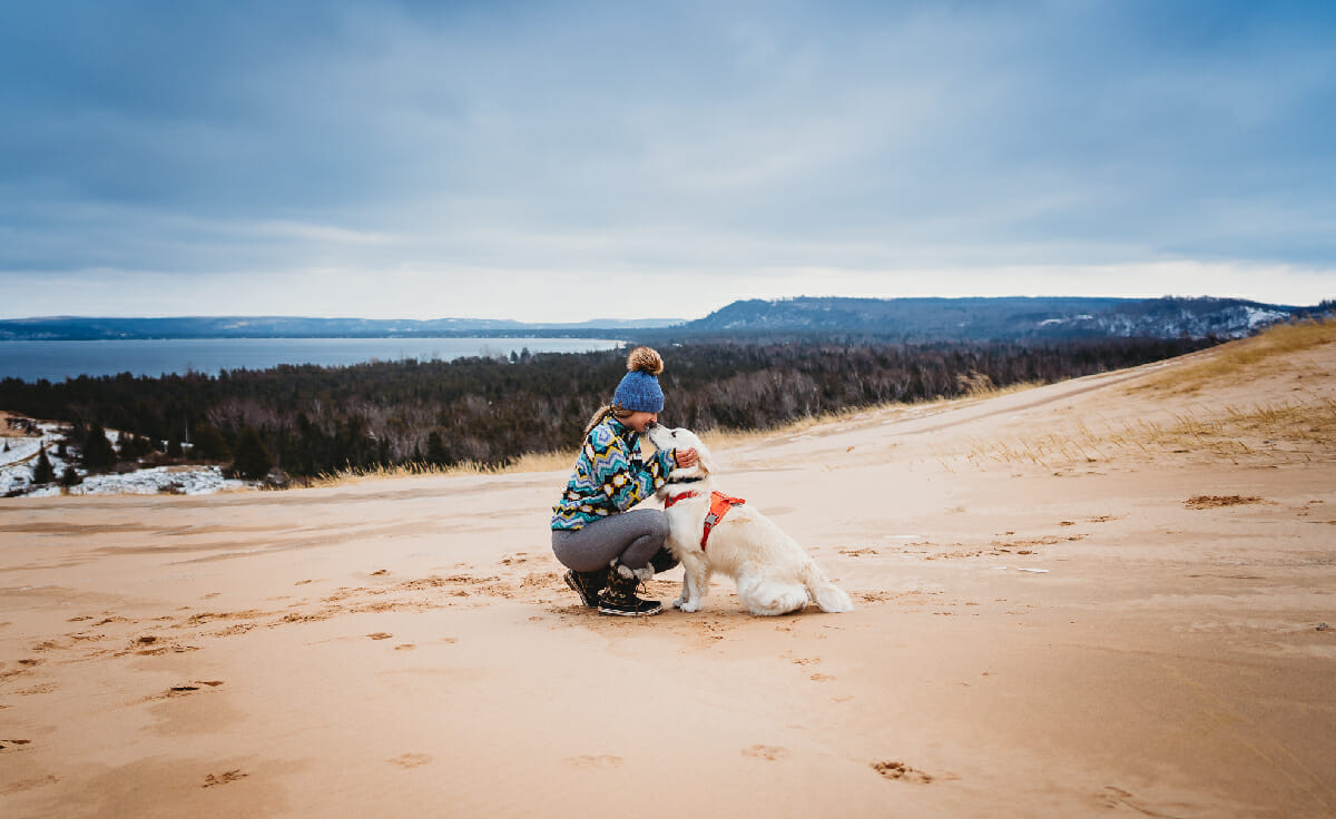 A woman and her dog sit together on an overlook