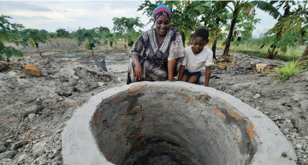 Forest garden farmer, Salma, and her son stand next to their new well
