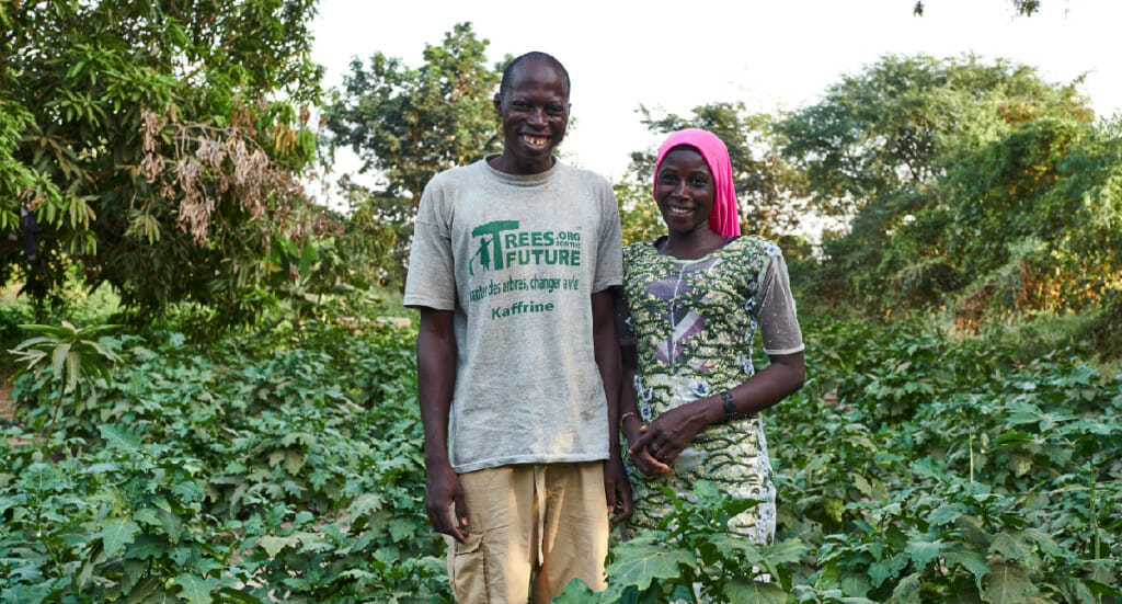 Two forest garden farmers stand in their garden