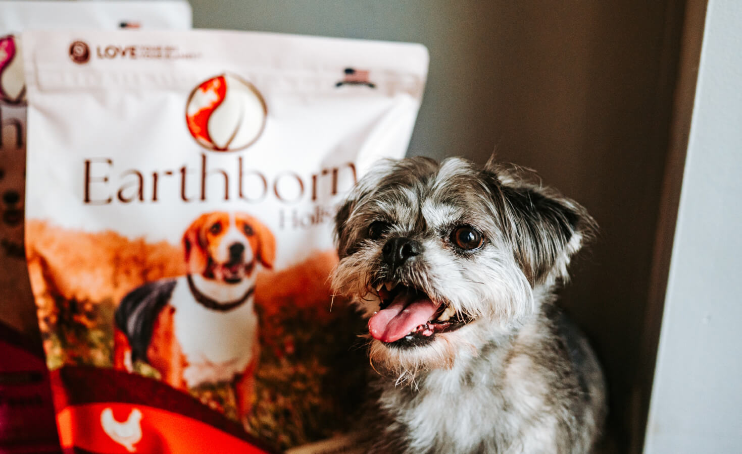 dog smiles next to bag of dog food