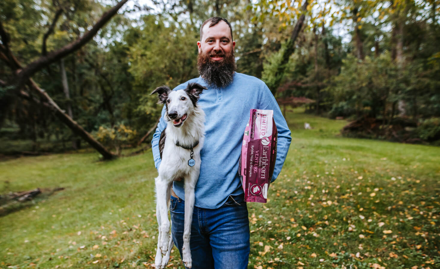 Person holds dog in one arm and dog food in the other arm