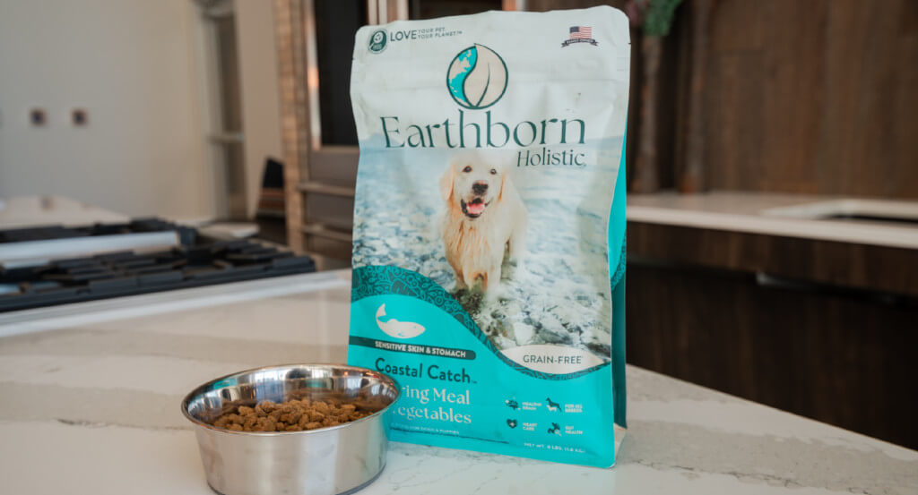 Bag of Earthborn Holistic Coastal Catch and bowl sit on counter top