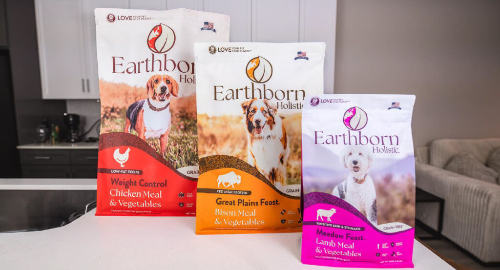 Three bags of Earthborn Holistic dog food sit on counter top