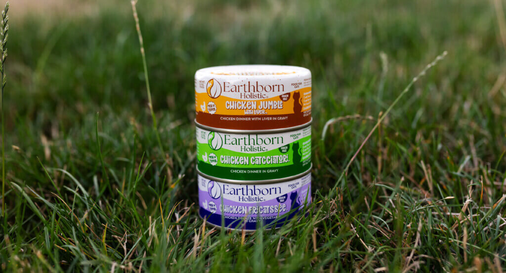 3 wet cat food cans stacked in the grass