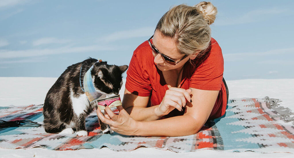 woman holding a can of Earthborn Holistic cat food for her cat to eat