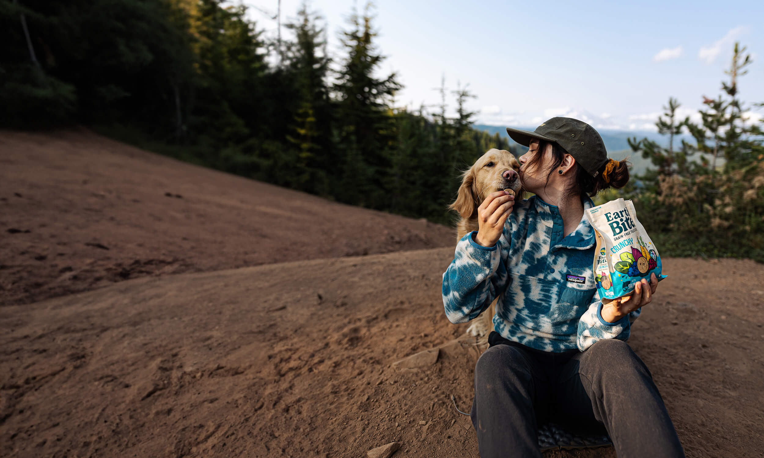 person holding a bag of EarthBites Crunchy Salmon kissing dog and giving him a treat