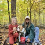 2 people sit outside while dog sits between them with EarthBites treats
