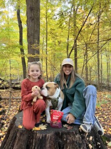 2 people sit outside while dog sits between them with EarthBites treats